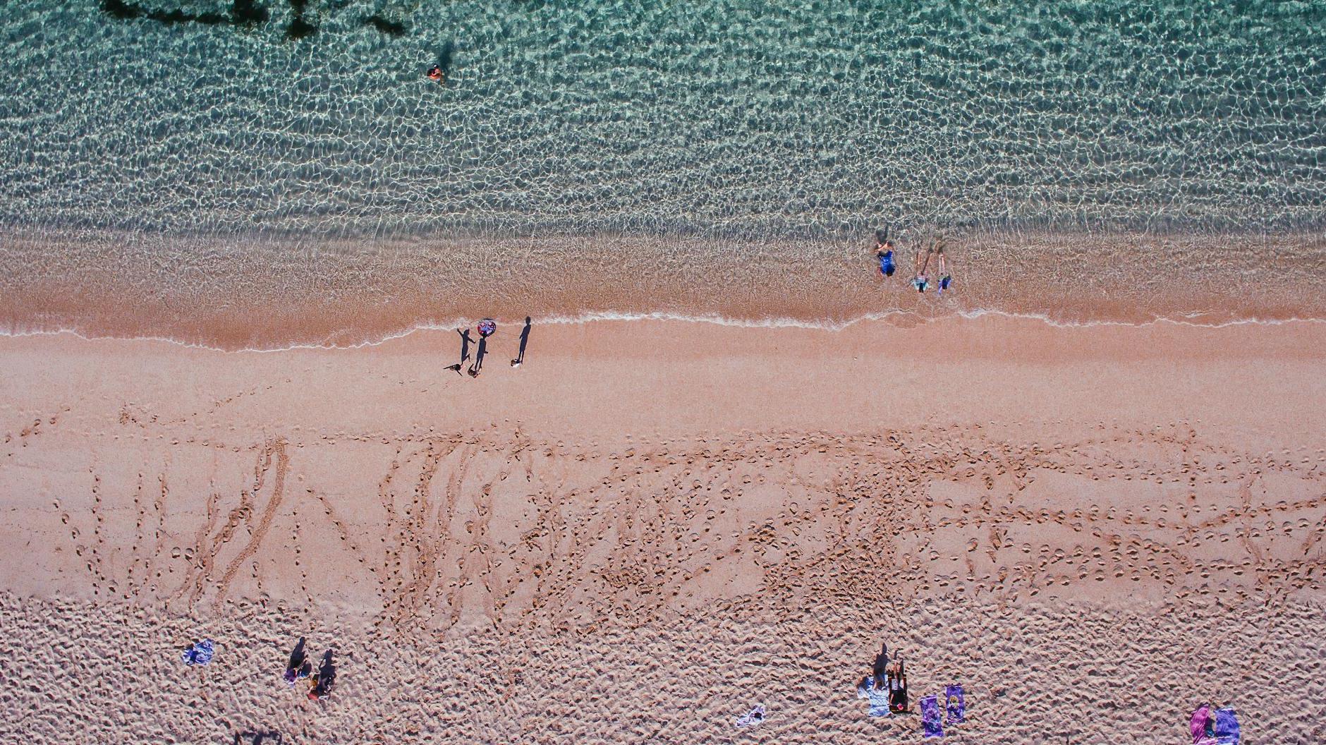 People strolling on sandy beach near azure rippling sea