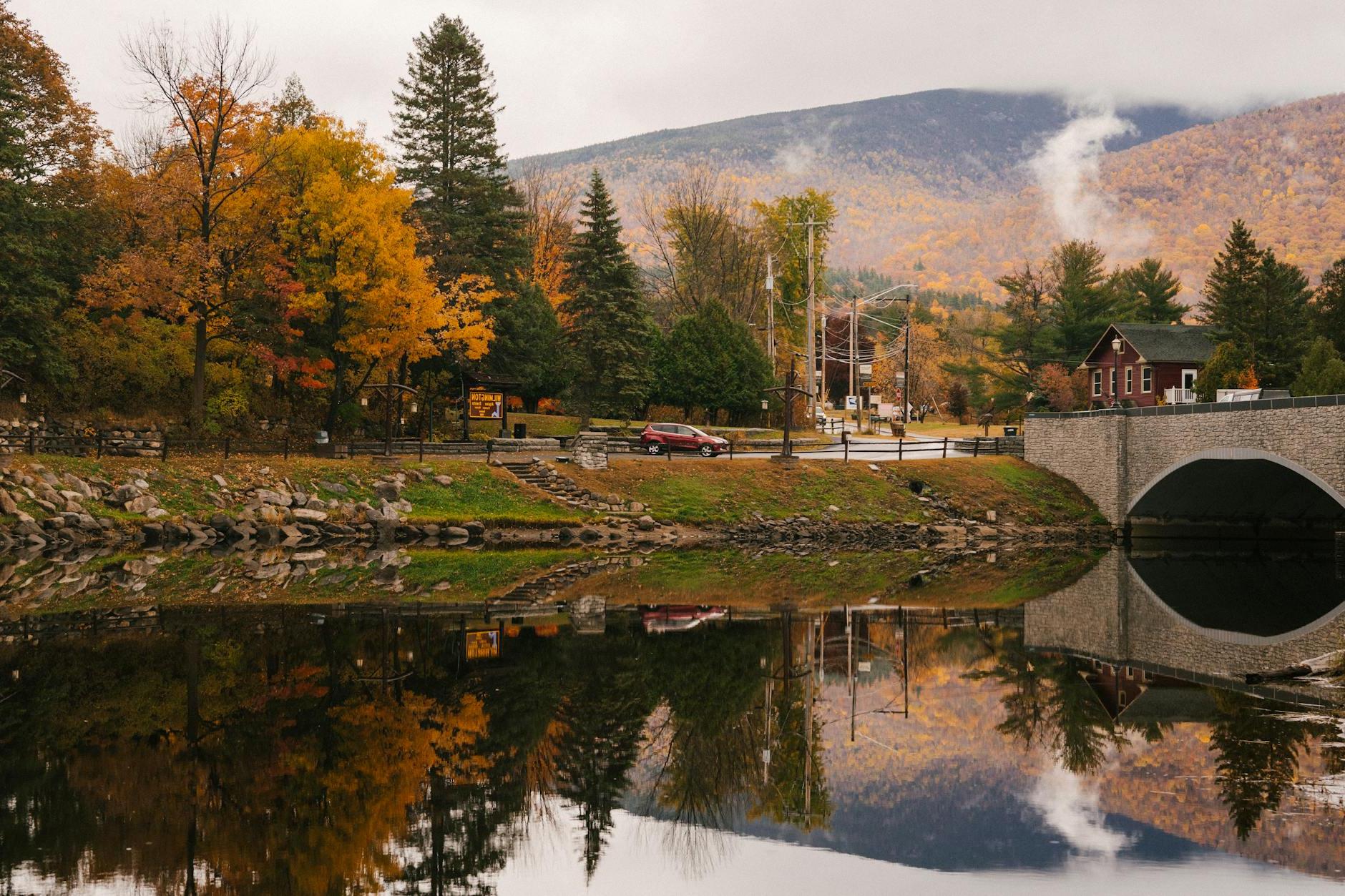 Bridge and trees reflecting in calm river in daytime