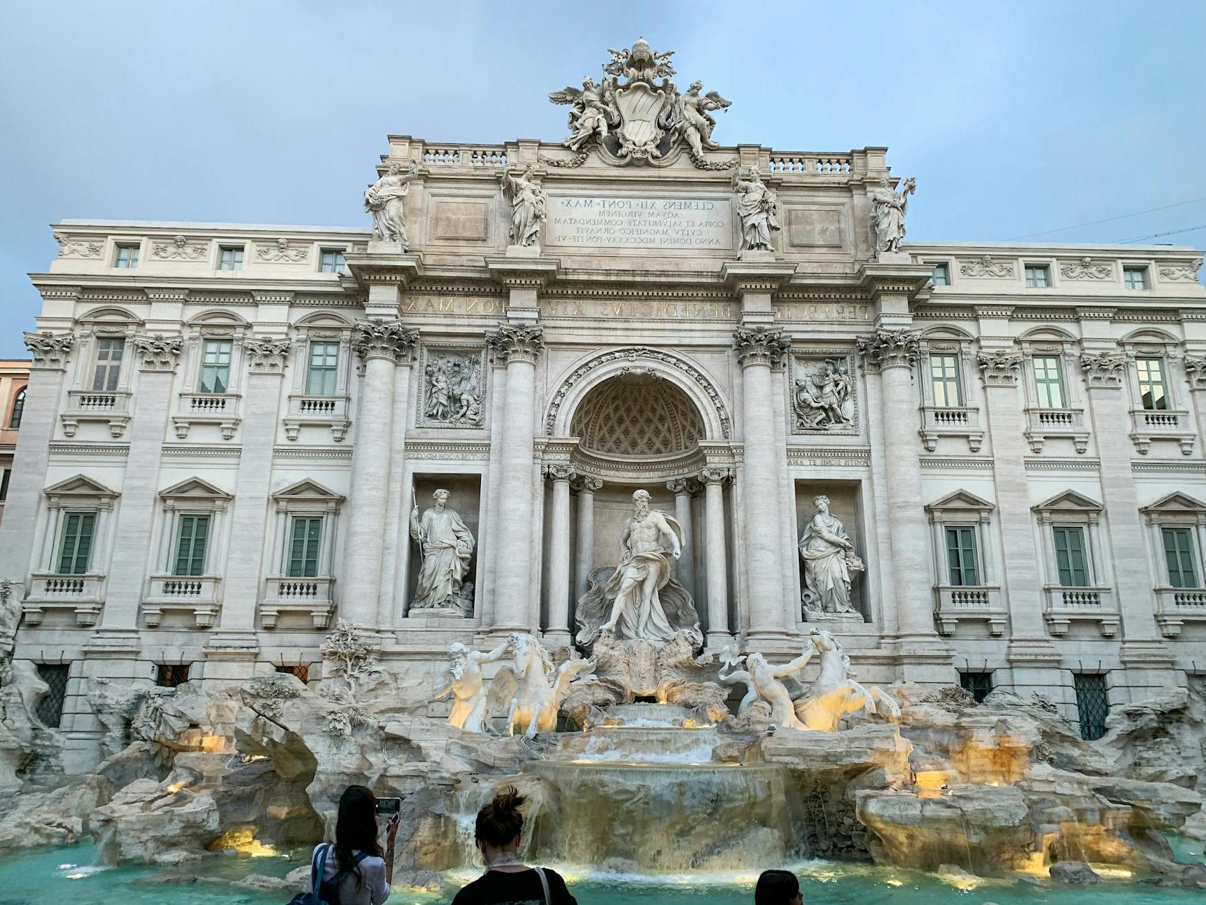 Majestic stone building and fountain with sculptures at dusk