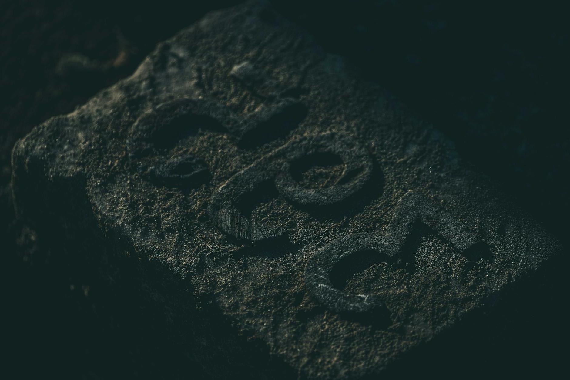 From above of rough textured stone with carved number placed on ground in misty cemetery