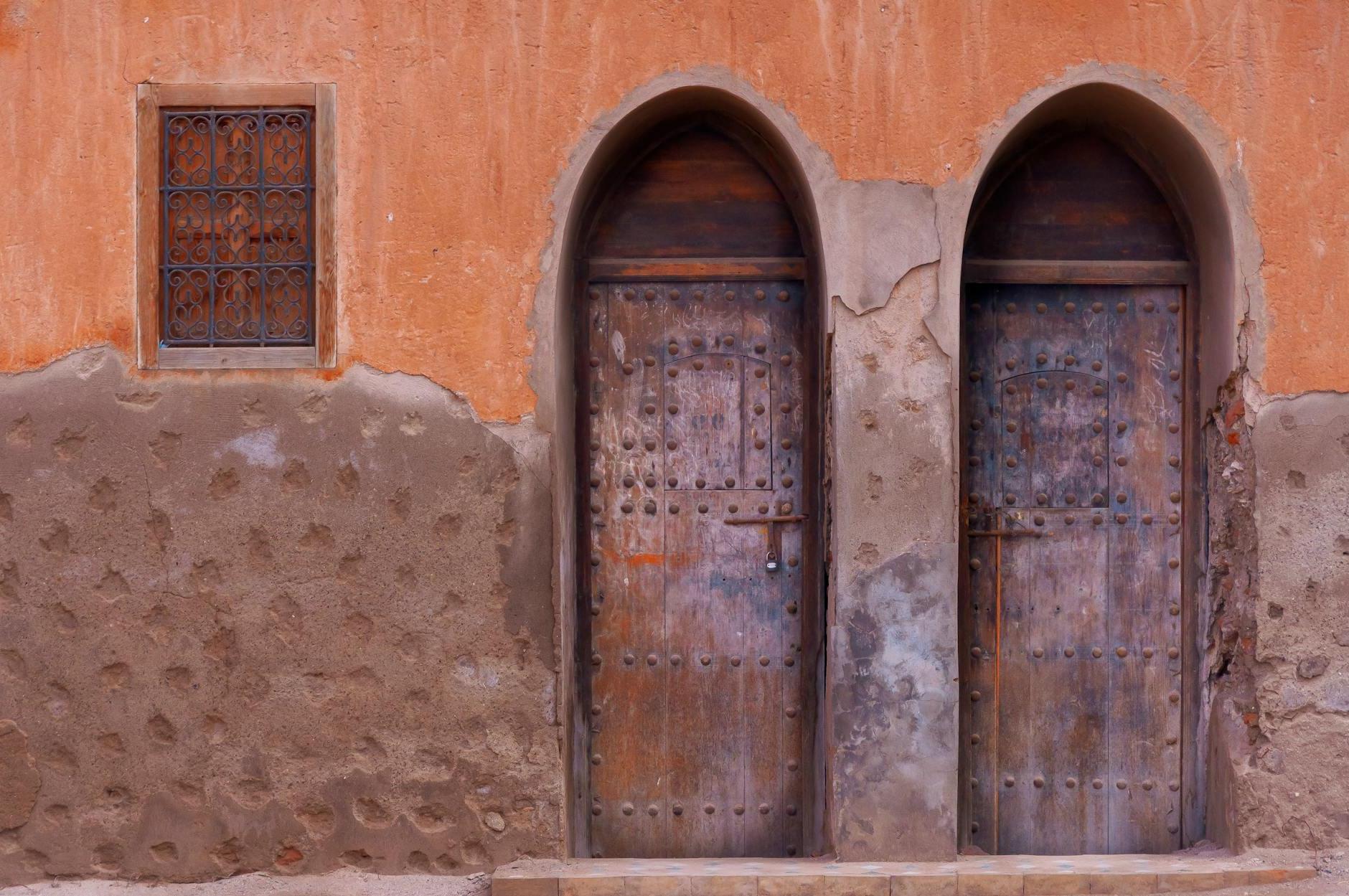 Exterior of weathered residential building with arched wooden doors in Morocco