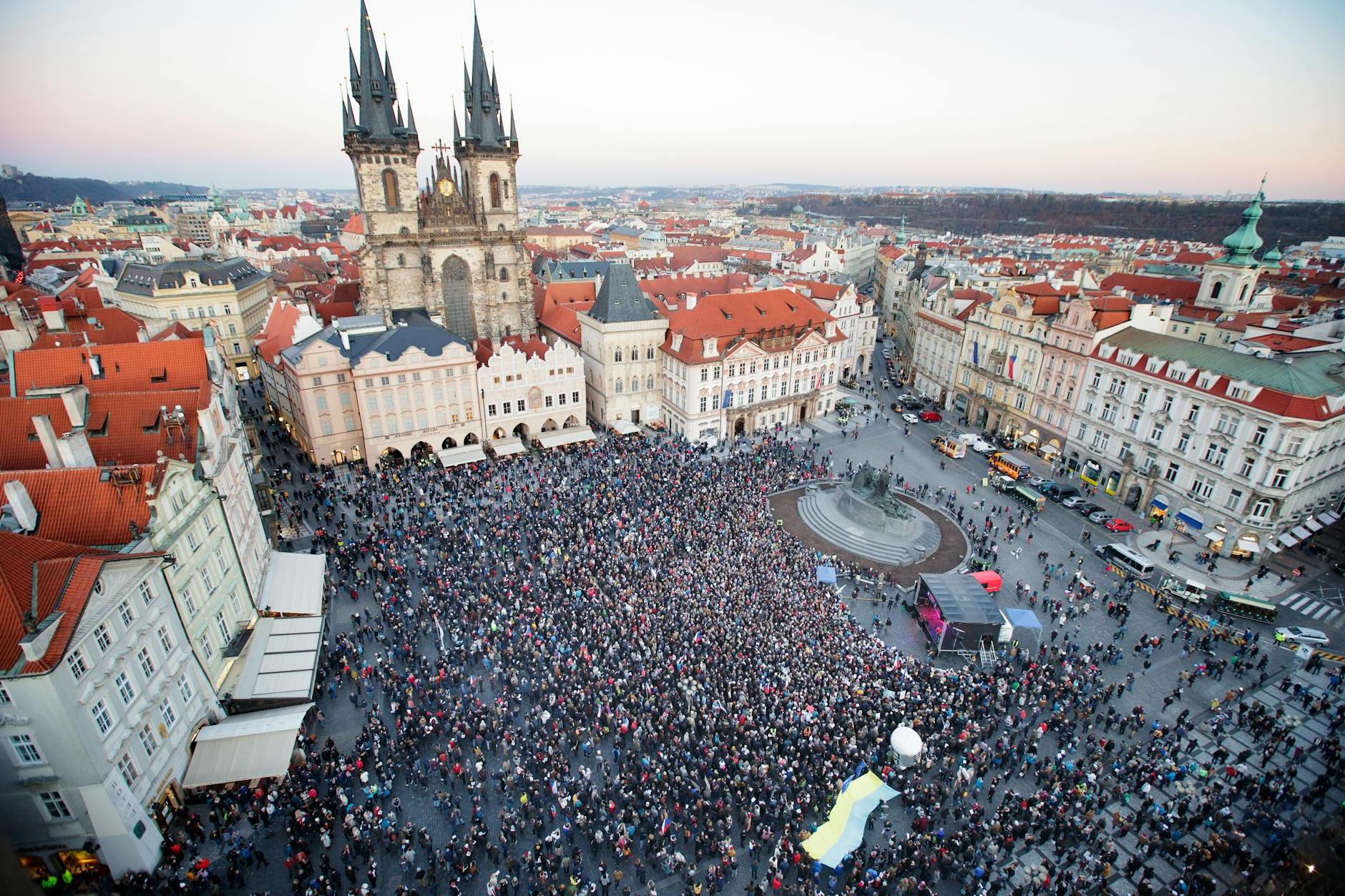 Drone view of crowd of people standing on square near gothic aged church and old town hall located in Prague