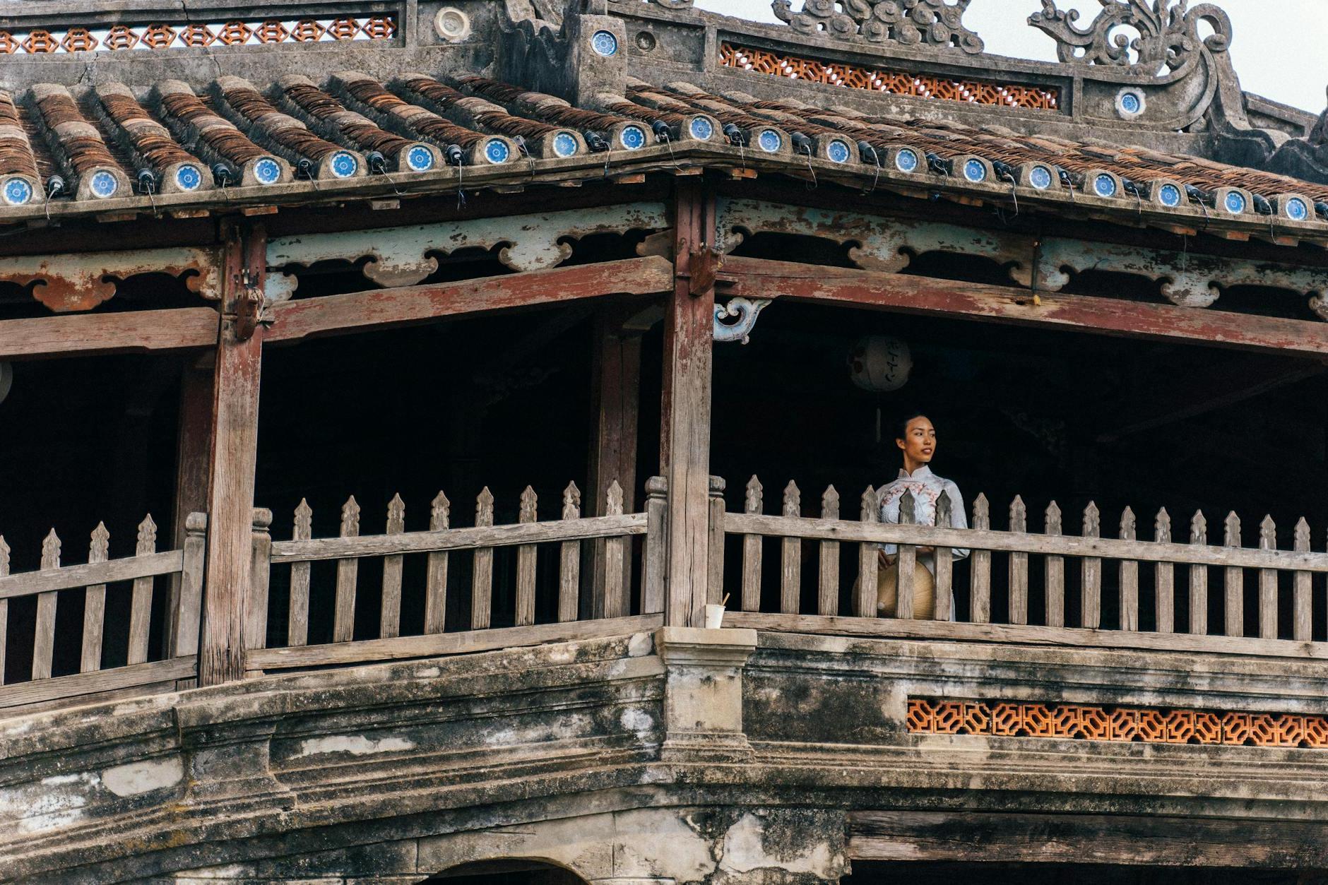 Woman in White Traditional Dress Standing on a Covered Bridge