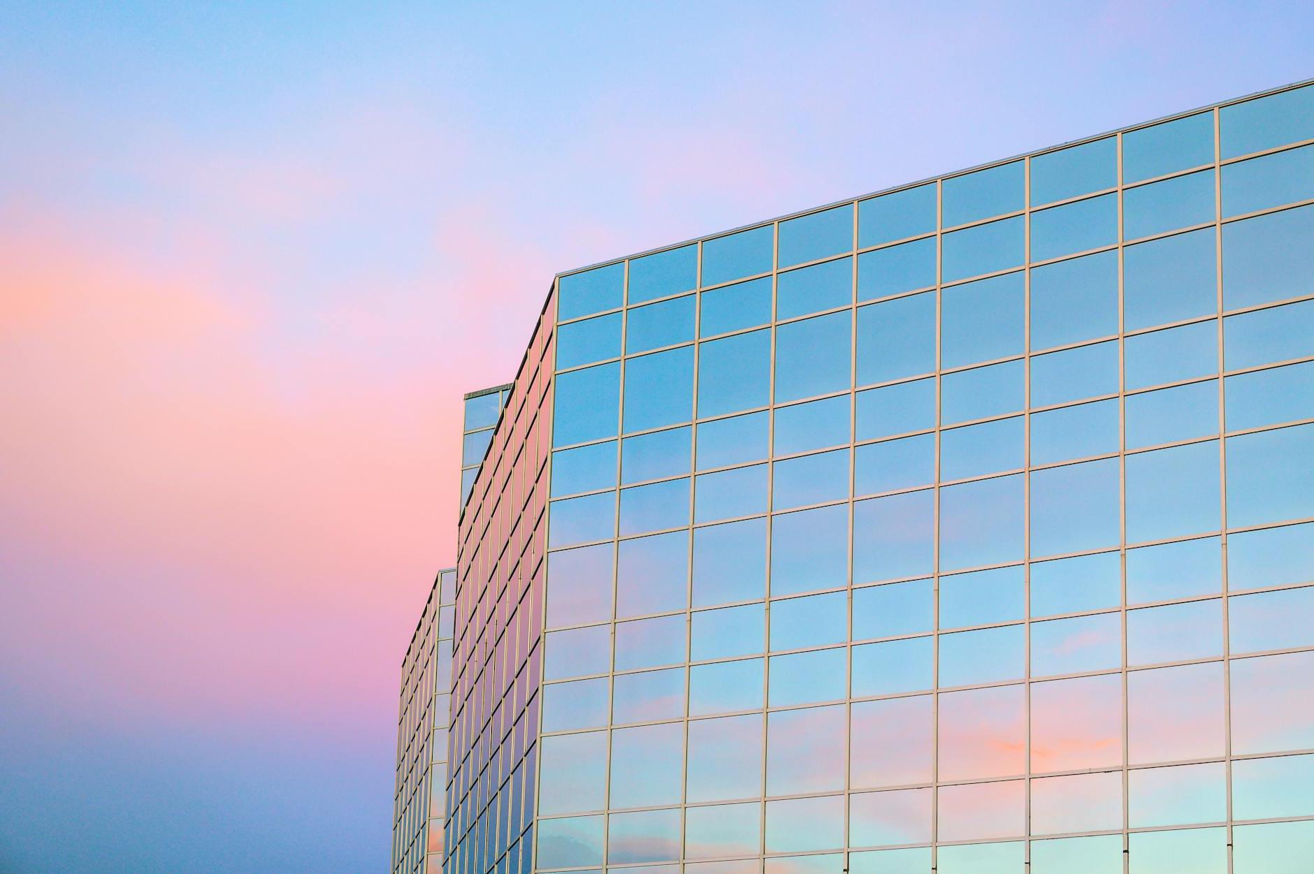 Exterior of contemporary building with glass mirrored walls located in city against colorful sky at sunrise time