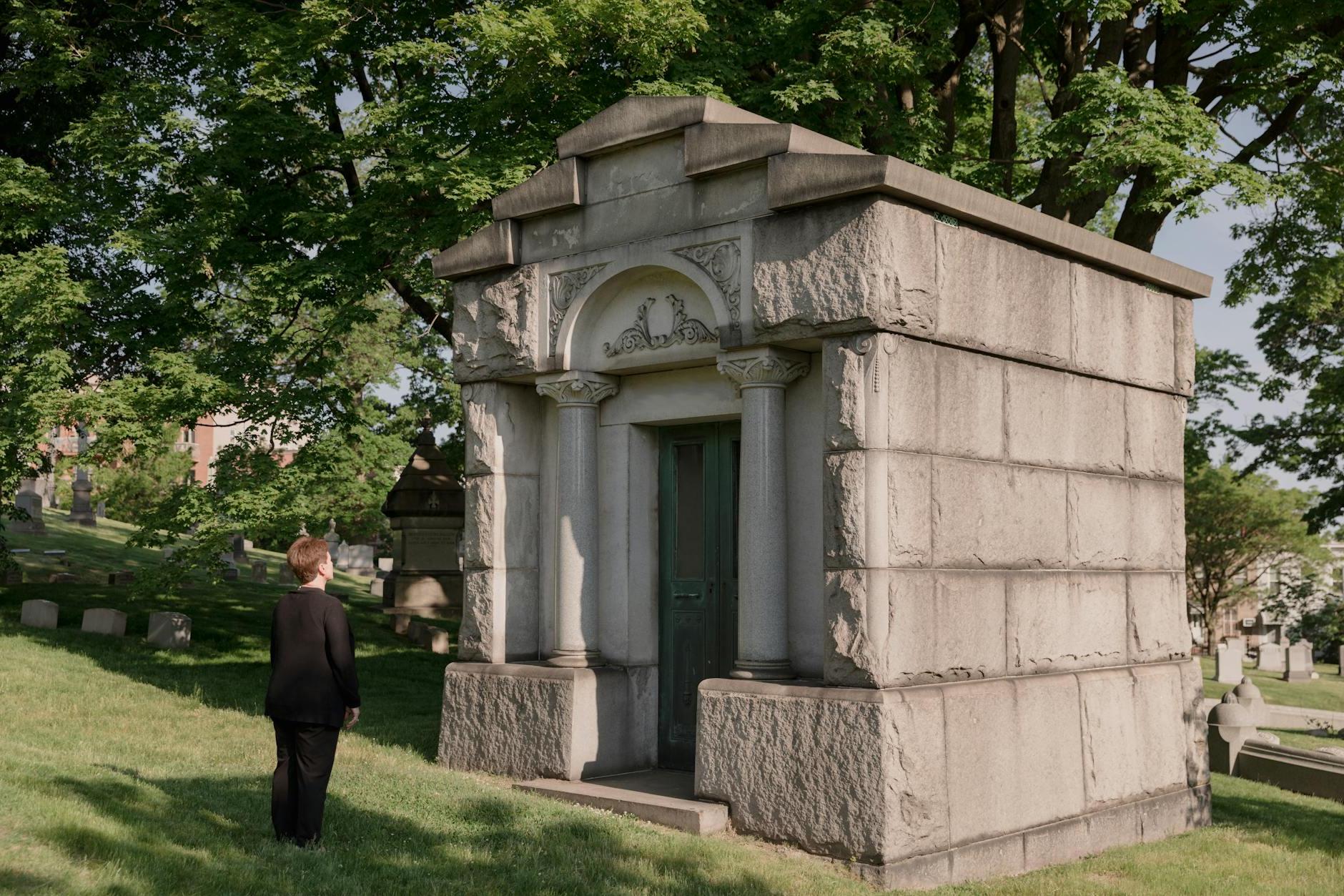 Woman In Black Outfit Standing In Front Of A Mausoleum