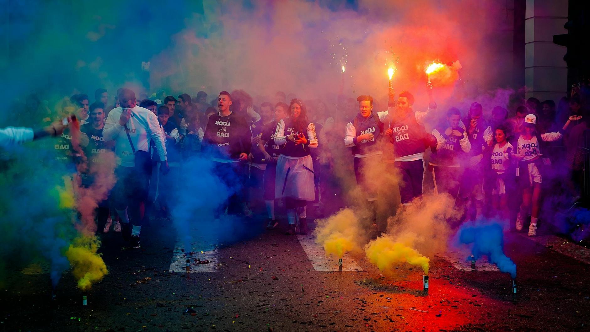 Group of People on Road With Assorted-color Smokes